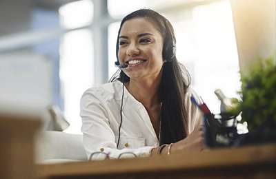Person wearing a headset and white shirt seated at a desk in a modern office.
